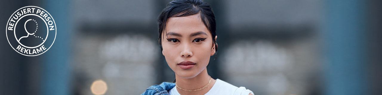 Makeup Trends illustrative banner image - portrait of a woman wearing statement Eyeliner, with jean jacket on shoulder